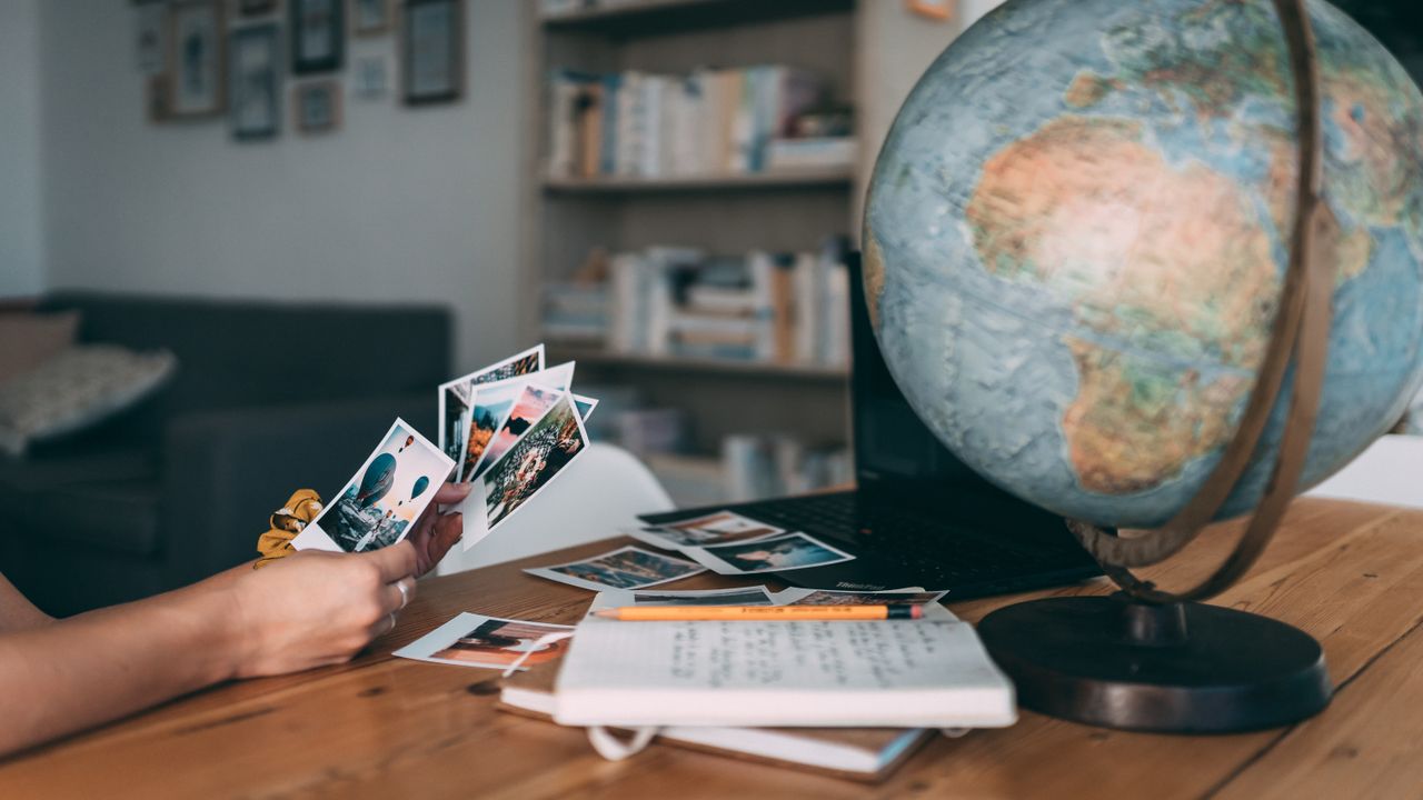 An inviting scene of exploring travel memories with Polaroid photos, globe, and notes.